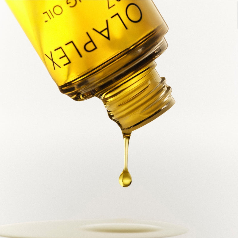 Golden hair oil dripping out of an OLAPLEX No.7 Bonding Oil™ bottle