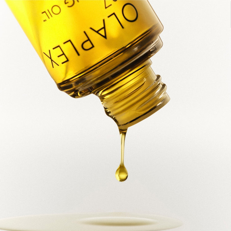 Golden hair oil dripping out of an OLAPLEX No.7 Bonding Oil™ bottle