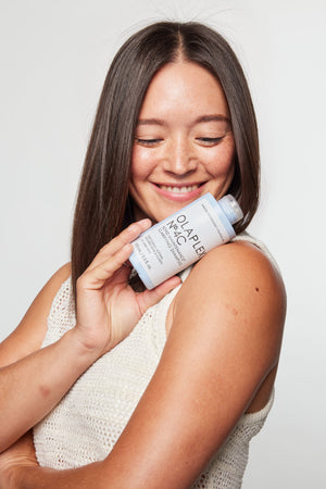 Woman holding No.4C Bond Maintenance Clarifying Shampoo bottle