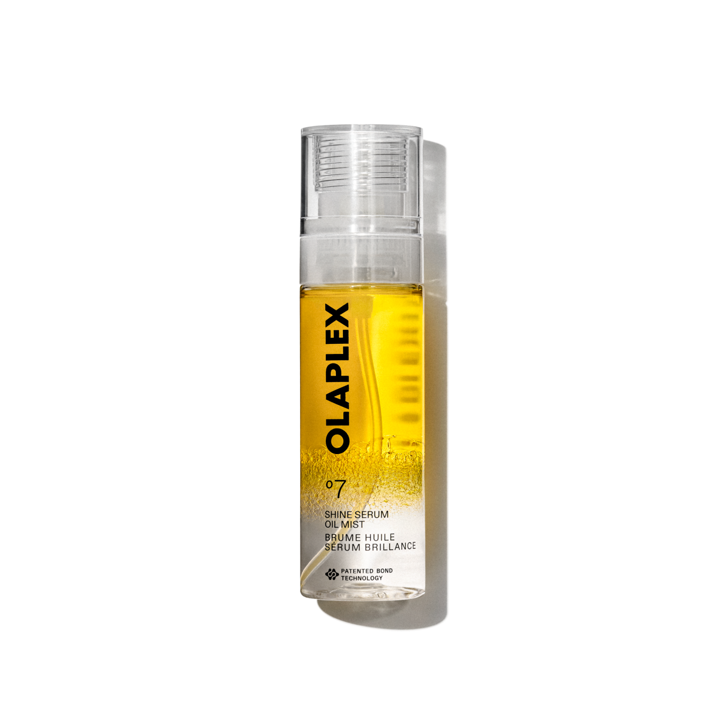 A product packshot of Olaplex No. 7 Shine Serum Oil Mist in an 80ml clear spray bottle. The bottle features a bright yellow liquid visible inside, a transparent cap, and a clean white label at the bottom with black text displaying the product name, details, and the signature "No. 7" logo. The bottle is isolated against a transparent grid background.